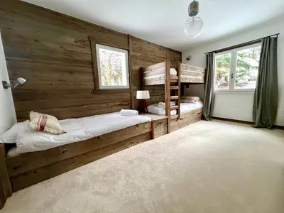 a bedroom with wooden walls and two bunk beds at Fairway in Megève