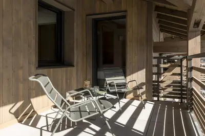 two chairs and a table on a balcony at Nid d'Aigle - Balcon avec vue Mont Blanc in Les Houches