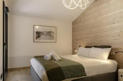 a bedroom with a large bed with a wooden wall at Nid d'Aigle - Balcon avec vue Mont Blanc in Les Houches