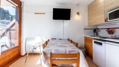 a small kitchen with a table and a television in a room at Les Eterlous N07 - 2P5 in Morillon