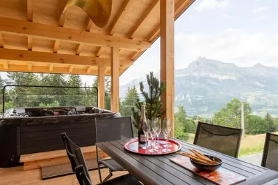 a table and chairs on a patio with a hot tub at Chalet Eteila vue incroyable ! Combloux 10 min de Megève in Combloux