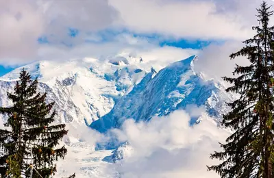 a snow covered mountain with two trees in the foreground at Chalet Eteila vue incroyable ! Combloux 10 min de Megève in Combloux