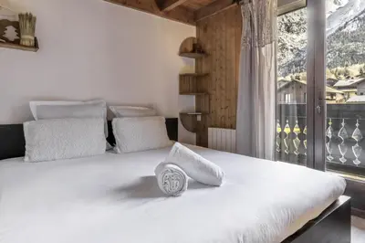 a bedroom with a large white bed with a window at Les Arolles - Duplex familial - Vue montagne in Les Houches