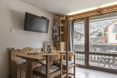 a dining room with a table and a balcony at Les Arolles - Duplex familial - Vue montagne in Les Houches