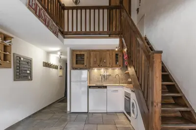 a kitchen with a refrigerator and a staircase at Les Arolles - Duplex familial - Vue montagne in Les Houches