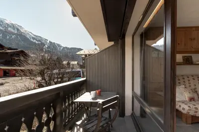 a balcony with a table and a view of a mountain at Les Arolles - Duplex familial - Vue montagne in Les Houches