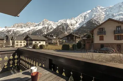 a cup of coffee sitting on a balcony with mountains at Les Arolles - Duplex familial - Vue montagne in Les Houches