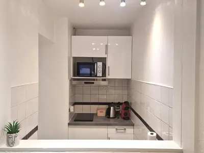 a small kitchen with white cabinets and a microwave at La Floria, Vue Mont Blanc in Chamonix-Mont-Blanc