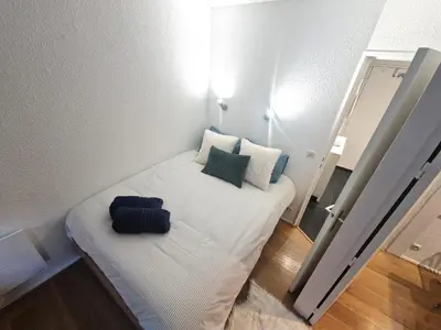 a small room with a bed with white sheets and pillows at La Floria, Vue Mont Blanc in Chamonix-Mont-Blanc