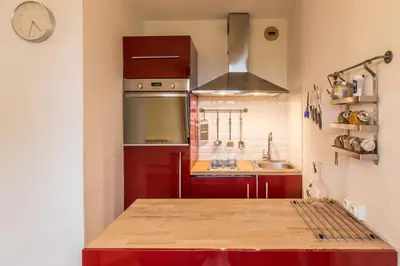 a small kitchen with red cabinets and a clock on the wall at Apartment Balme 3B - A Chamonix Mont Blanc Haven in Chamonix-Mont-Blanc