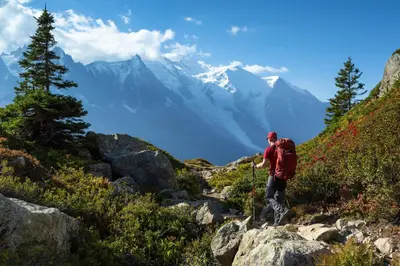 a man walking on a mountain trail with mountains in the background at Résidence Grand Roc - Ancolies 348 - Happy Rentals in Chamonix-Mont-Blanc