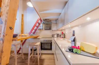 a large kitchen with white counters and a staircase at Résidence Grand Roc - Ancolies 348 - Happy Rentals in Chamonix-Mont-Blanc