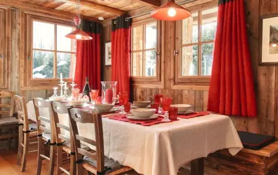 a dining room with a table and red curtains at Chalet Foret Rouge in Chamonix-Mont-Blanc