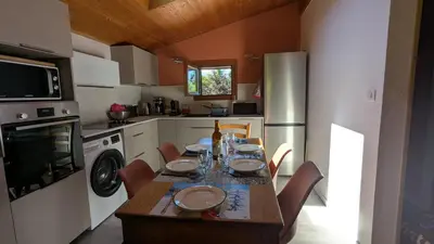 a kitchen with a table with chairs and a refrigerator at les Cristaux in Combloux