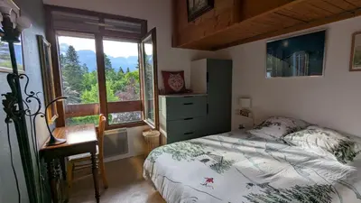 a bedroom with a bed and a large window at les Cristaux in Combloux