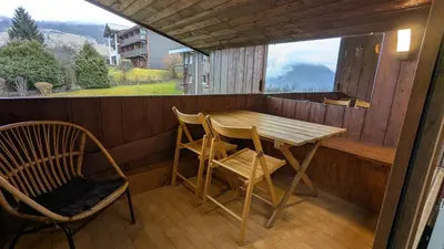 a small porch with a wooden table and chairs at les Cristaux in Combloux