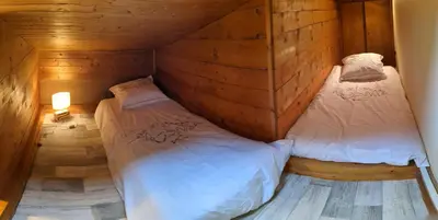 two beds in a room with wooden walls at les Cristaux in Combloux