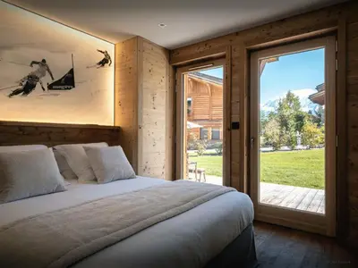 a bedroom with a large bed and a large window at Chalet Ellambra - OVO Network in Combloux