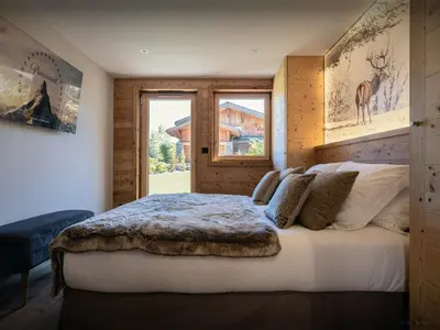 a bedroom with a large bed with a window at Chalet Ellambra - OVO Network in Combloux