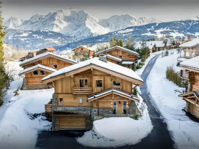 a log cabin in the snow with mountains in the background at Chalet Ellambra - OVO Network in Combloux