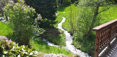 a stream of water in a field next to a bridge at Les Vardasses - Chalet typique avec jardin et vue sur les montagnes in Les Houches