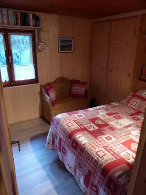 a bedroom with a bed and a chair in it at Les Vardasses - Chalet typique avec jardin et vue sur les montagnes in Les Houches