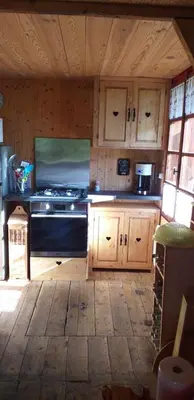 a kitchen with a stove and wooden cabinets at Les Vardasses - Chalet typique avec jardin et vue sur les montagnes in Les Houches