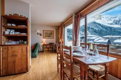 a dining room with a table and a large window at Nice apartment with Mont Blanc balcony's view in Chamonix-Mont-Blanc