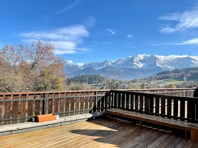 a bench sitting on top of a wooden deck with mountains at Cocon alpin in Cordon