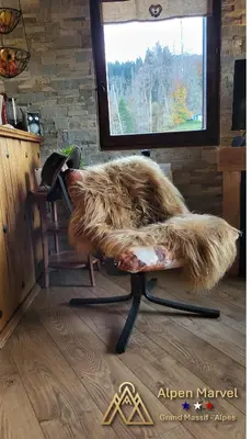 a chair covered in fur sitting in front of a window at Alpen Marvel in Morillon