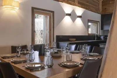 a large wooden table with chairs and glasses on it at Ferme des Tétras - Chalet de prestige en montagne in Saint-Gervais-les-Bains