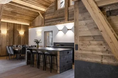 a restaurant with wooden walls and a bar with stools at Ferme des Tétras - Chalet de prestige en montagne in Saint-Gervais-les-Bains