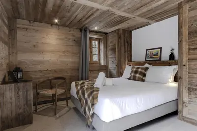 a bedroom with a white bed and a wooden wall at Ferme des Tétras - Chalet de prestige en montagne in Saint-Gervais-les-Bains