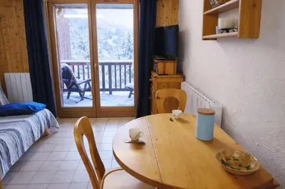 a wooden table and chairs in a room with a balcony at Apartment near city center in Saint-Gervais-les-Bains