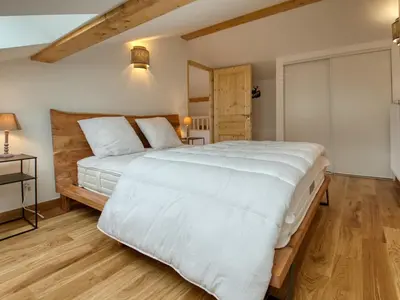 a bedroom with a large white bed and wooden floors at Bel appartement neuf 8 pers, Samoëns, près village, WIFI inclus - FR-1-642-100 in Samoëns