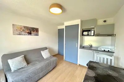 a living room with a couch and a kitchen at Au Pied des Neiges in Demi-Quartier