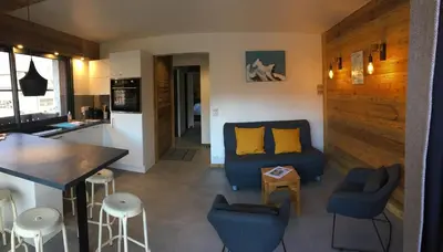 a living room with a blue couch and a kitchen at Le Samoëns cosy 3 etoiles en centre ville in Samoëns