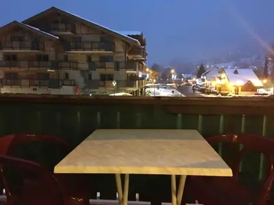 a table and chairs on a balcony with a building at Le Samoëns cosy 3 etoiles en centre ville in Samoëns