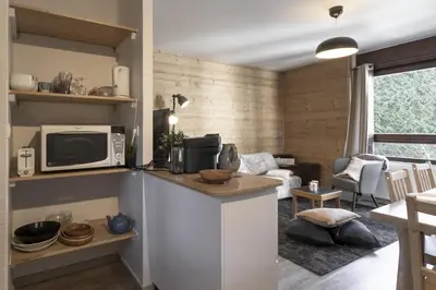 a kitchen with a counter with a microwave and a living room at Le Castel des Roches - Sejour ski & spa in Saint-Gervais-les-Bains