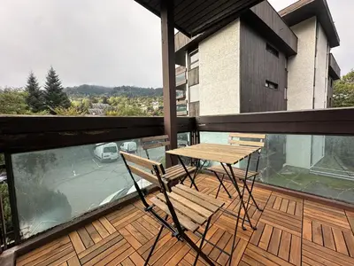 a balcony with a wooden table and chairs on a balcony at Le Castel des Roches - Sejour ski & spa in Saint-Gervais-les-Bains
