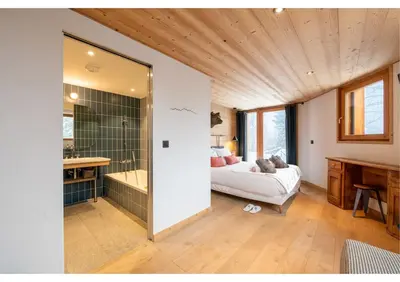 a bedroom with a bed and a bathroom with a tub at Chalet Croc Blanc, Chamonix - vu massif exceptionnel in Les Houches