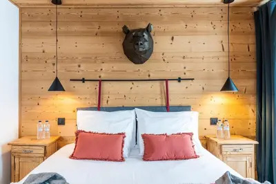 a bedroom with a wooden wall with a bed with red pillows at Chalet Croc Blanc, Chamonix - vu massif exceptionnel in Les Houches