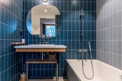 a blue tiled bathroom with a tub and a sink at Chalet Croc Blanc, Chamonix - vu massif exceptionnel in Les Houches