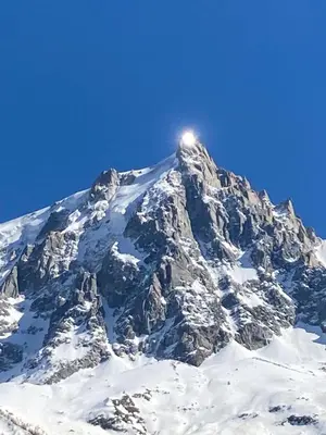 a mountain covered in snow with the sun on top at Chamonix Centre - Sophisticated 2-Bedroom Duplex in Chamonix-Mont-Blanc