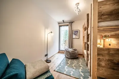 a room with two bunk beds and a blue chair at Apartment Aubretia, Les Houches - by EMERALD STAY in Les Houches