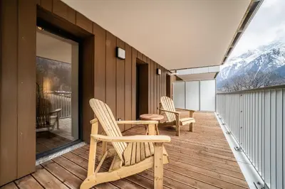 an outdoor deck with a table and chairs on a building at Apartment Aubretia, Les Houches - by EMERALD STAY in Les Houches