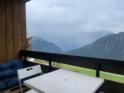a table and chair on a balcony with a view of mountains at Appartement 4 personnes Samoëns 1600 in Samoëns