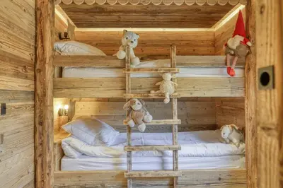 two bunk beds in a wooden room with teddy bears at Chalet Boucle in Megève