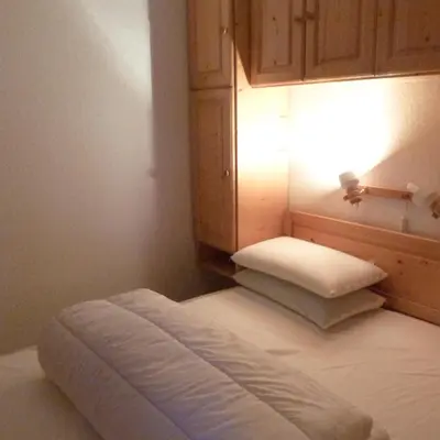 a room with a bed with a light and a cabinet at LES JARDINS ALPINS CHEZ Olivier in Saint-Gervais-les-Bains