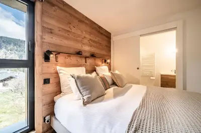 a bedroom with a large white bed with a wooden wall at Apartment Cumaru, Les Houches - by EMERALD STAY in Les Houches